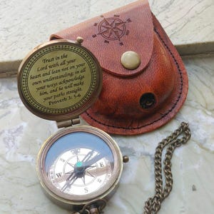 May include: A brass pocket compass with a chain and a brown leather pouch. The compass lid features the engraved text: Trust in the Lord with all your heart and lean not on your own understanding; in all your ways acknowledge him, and he will make your paths straight. Proverb 3: 5-6.