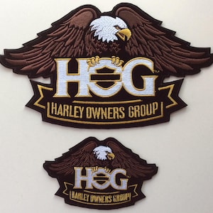 May include: Two embroidered patches featuring a bald eagle with brown wings and a white head. The text HOG is in white with a gold outline, and the text HARLEY OWNERS GROUP is in gold. The patches are black with a gold banner border design.