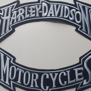 Puede incluir: Dos parches bordados con el texto Harley-Davidson y Motorcycles en hilo blanco sobre un fondo negro. El parche superior está arqueado con el nombre de la marca, mientras que el parche inferior está arqueado con la palabra Motorcycles en letras.