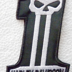 May include: A black and white embroidered patch in the shape of the number one. The top of the number features a white skull design, while the base contains the text HARLEY-DAVIDSON in black lettering against a white background with a black border.