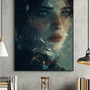 May include: A framed art print featuring a woman's face with striking blue eyes and red lips. The artwork has a dark, abstract style with fragmented, textured elements. The print is displayed on a gray wall above a dark gray cabinet.