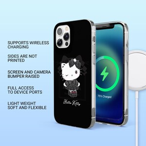 May include: Black phone case featuring a Hello Kitty design. The case has a black background with a white Hello Kitty graphic and the text "Hello Kitty". The phone screen shows a charging symbol. The case supports wireless charging and has full access to device ports.