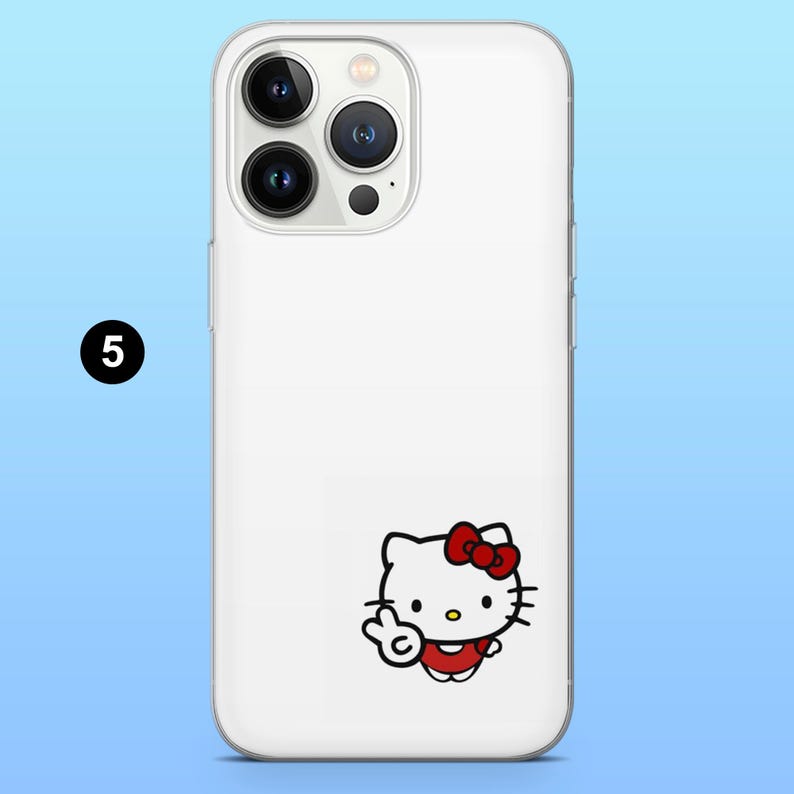 May include: White phone case featuring a Hello Kitty graphic. The cartoon character is wearing a red dress and bow, and is giving a peace sign. The phone case has a clear border and a camera cutout.