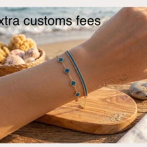 Puede incluir: Dos pulseras de tono dorado con pequeños detalles cuadrados de color turquesa. Una pulsera tiene una cadena delicada con dijes cuadrados espaciados, mientras que la otra es un diseño de barra fina y sólida. El texto "No extra customs fees" es visible.