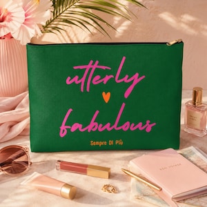 Könnte beinhalten: Eine rechteckige, dunkelgrüne Reißverschlusstasche mit dem pinkfarbenen Schriftzug "utterly fabulous", einem kleinen orangefarbenen Herz in der Mitte und dem orangefarbenen Text "Sempre Di Più" am unteren Rand. Der Reißverschluss hat einen goldenen Zipper.