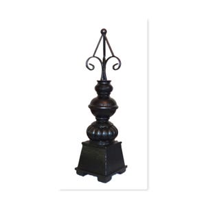 May include: A dark bronze decorative finial with a square base, a bulbous midsection, and a pointed top with a decorative flourish. The finial is made of metal and has an aged appearance, suitable for home decor.