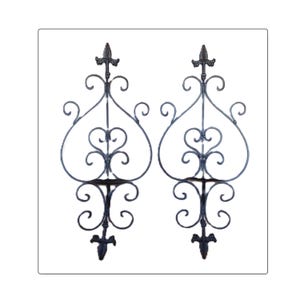 May include: Two ornate, dark metal decorative panels. Each panel features a central heart-shaped design with scrolling details, topped with a fleur-de-lis and a similar design at the base. The panels are symmetrical and suitable for interior or exterior decor.