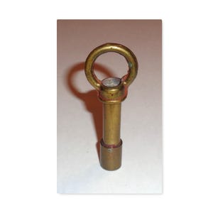 May include: A vintage brass key with a circular handle and a cylindrical body. The key has a tarnished appearance, with hints of red and green oxidation. The key is likely used for a lock or mechanism.