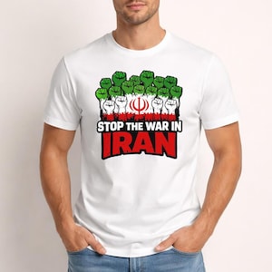 Puede incluir: Camiseta blanca con un diseño gráfico que presenta puños verdes y blancos, la bandera iraní y el texto "STOP THE WAR IN IRAN" en rojo y blanco. La camiseta es de cuello redondo.