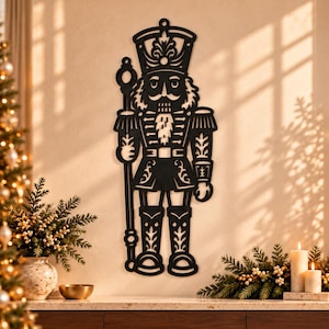 May include: A black, flat, laser-cut metal wall decoration shaped like a nutcracker soldier. The figure wears a tall hat, a uniform with epaulets, and holds a tall staff. The design features intricate cutouts throughout the entire body.