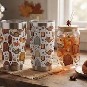 May include: Two stainless steel tumblers and one clear glass tumbler with a bamboo lid and straw. The tumblers feature a repeating pattern of autumn-themed illustrations including jumpers, slippers, pumpkins, candles, and fall leaves.