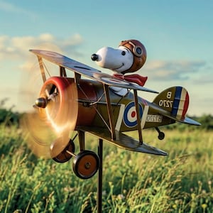 Puede incluir: Figura metálica de Snoopy en un biplano con hélice giratoria. El avión es verde oliva con detalles rojos y azules, y Snoopy lleva un casco de aviador marrón y una bufanda roja. El fondo es un campo de hierba verde bajo un cielo azul.