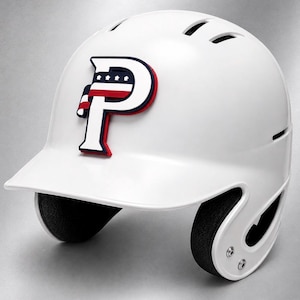 May include: A white baseball batting helmet featuring a prominent letter P logo on the front. The logo is white with a dark blue outline and a red, white, and blue horizontal stripe detail containing four small white stars across the top section.