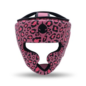 May include: Pink leopard print boxing headgear with black accents. The headgear features a black logo on the front and is designed to protect the head during training or competition. The design includes a chin strap and ear protection.