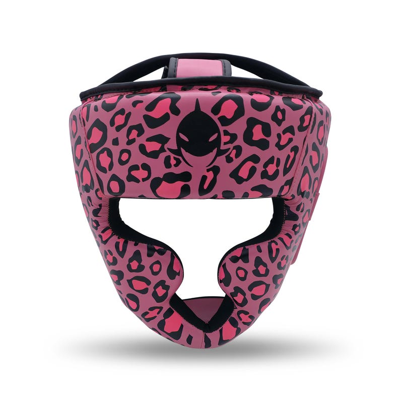 May include: Pink leopard print boxing headgear with black accents. The headgear features a black logo on the front and is designed to protect the head during training or competition. The design includes a chin strap and ear protection.