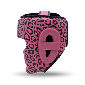 May include: A pink leopard print headgear with black accents. The headgear features a padded ear protector and a chin strap. The design includes a pink and black leopard print pattern, offering protection and style for combat sports.