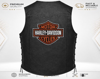Peut inclure: Un gilet en cuir noir arborant le logo Harley-Davidson Motor Cycles imprimé en orange et blanc au dos. Le gilet présente des détails de laçage sur les côtés avec des cordons noirs et une coupe sans manches classique à encolure arrondie.