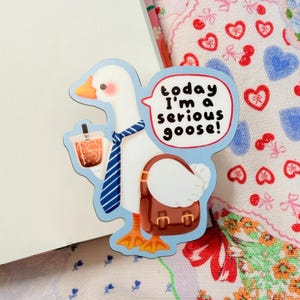 May include: A whimsical sticker featuring a white goose with an orange beak and feet, wearing a blue striped tie and carrying a brown briefcase and a bubble tea. Text reads "today I'm a serious goose!"