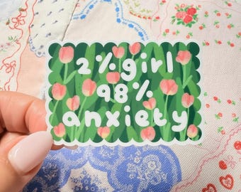 May include: A rectangular sticker with a green scalloped edge. The sticker has a floral design with pink tulips and the text "2% girl 98% anxiety" in white. The sticker is held by a person.
