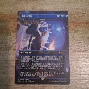 May include: A Magic: The Gathering card featuring a woman in a black dress with a feathered collar, casting a spell. The card has Japanese text and a blue and purple color scheme. The card is titled "Witch's Foresight."
