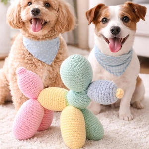 Peut inclure: Deux chiens, un caniche et un Jack Russell Terrier, sont assis sur un tapis blanc, chacun portant un bandana bleu. Un jouet pour chien en forme de ballon, crocheté et coloré, rose pastel, jaune, vert et bleu, est posé entre eux. Les chiens tirent la langue.