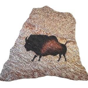 May include: A flat, irregularly shaped piece of natural sandstone with a rough, textured surface in shades of tan, brown, and gold. A painted illustration of a bison in black and dark brown is centered on the stone, facing toward the left.