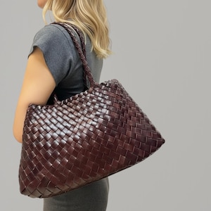 May include: A white ceramic mug with a black handle and the text "But First, Coffee" in a bold, black font. The mug is set against a blurred background, suggesting a cozy setting. The mug appears to be approximately 4 inches tall.