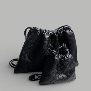 May include: Two black drawstring bags with a woven design. The larger bag has backpack straps, and the smaller bag has a single handle. Both bags are made of a soft, textured material.