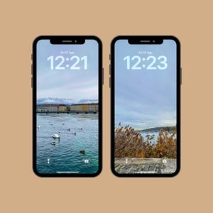 Pode incluir: Dois smartphones pretos exibindo papéis de parede de paisagens. Um mostra um lago com edifícios e pássaros, o outro uma vista da orla com plantas. Ambos os telefones exibem a data e a hora: Sex 17 Abr, 12:21 e 12:23.