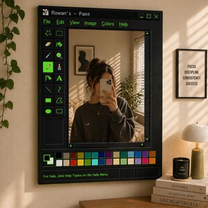 May include: A rectangular wall mirror featuring a black frame designed to resemble the user interface of a classic computer paint program. The border includes a toolbar with green icons, a color palette, and the text Rowan's - Paint at the top.