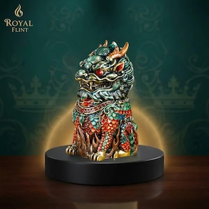 Puede incluir: Una detallada y colorida figura de una criatura m&iacute;tica, posiblemente un drag&oacute;n o un le&oacute;n, con ojos rojos, cuernos dorados y patrones intrincados en verde, rojo y dorado. La figura est&aacute; sobre una base circular negra, con el logo "Royal Flint".