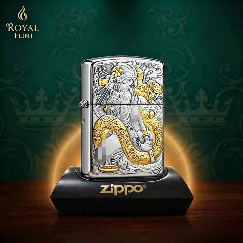May include: A silver Zippo lighter with a detailed engraved design featuring a woman and a golden snake. The lighter is on a black stand with the Zippo logo. The Royal Flint logo is in the upper left corner.