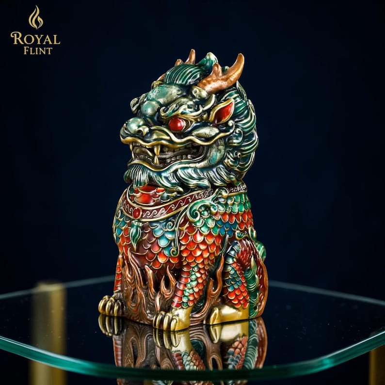Puede incluir: Figurita detallada y colorida de una criatura m&iacute;tica con apariencia de drag&oacute;n. La escultura presenta detalles en rojo, verde y dorado, con el texto "ROYAL FLINT" en la esquina superior izquierda. La figurita se exhibe sobre una superficie de vidrio.
