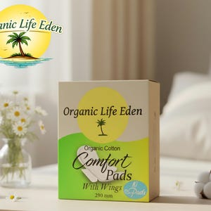 May include: A box of "Organic Life Eden Comfort Pads" with wings, made of organic cotton. The box is beige with a yellow circle and green accents. The text on the box includes "10 Pads" and "290 mm".