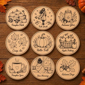 May include: A set of nine circular wooden coasters featuring black line art illustrations of autumn themes. Designs include a pumpkin patch, a person walking, a candle, maple leaves, a large pumpkin, apples, a coffee mug, a person, and acorns.