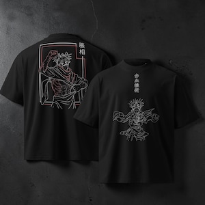 May include: Black t-shirts with white and red line art designs. One shirt features a character illustration with Japanese text, and the other has a similar design on the back. The shirts have a crew neck and short sleeves.