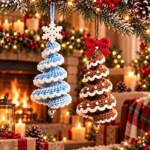 Ice blue crochet spiral tree with snowflake topper and brown gingerbread spiral tree with white icing edge and red bow hanging by a fireplace