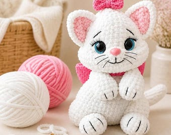 May include: A white crocheted cat plush toy with large blue eyes, long black eyelashes, and a pink nose. The cat features pink inner ears, a pink bow on its head, and a pink collar. It is crafted from soft, textured yarn with visible stitching.