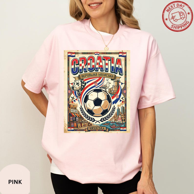 A woman wearing a pink t-shirt with a graphic design depicting a soccer ball and various elements associated with Croatia, such as flags and buildings.