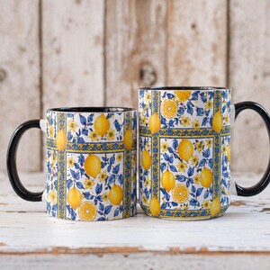 Two matching mugs with a floral pattern of yellow lemons and blue flowers are placed side by side on a wooden surface.