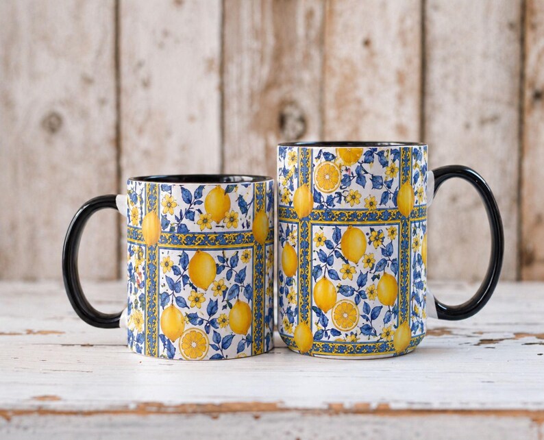 Two matching mugs with a floral pattern of yellow lemons and blue flowers are placed side by side on a wooden surface.
