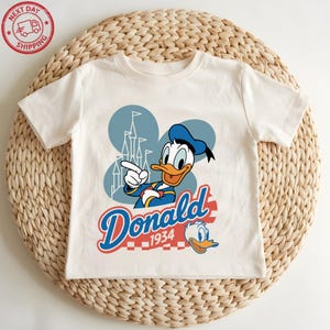 A white t-shirt with a cartoon image of a duck and the text "Donald" and "1934" printed on it.