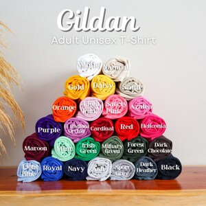 A pyramid-shaped arrangement of colorful rolled-up shirts, each with a different color, displayed on a wooden surface.