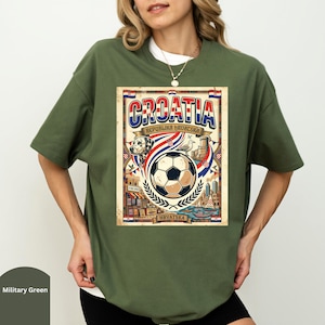 A woman wearing a green t-shirt with a graphic design featuring a soccer ball, a flag, and a cityscape.