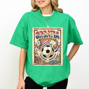 A woman wearing a green t-shirt with a graphic design featuring a soccer ball, a flag, and various elements associated with the country of Croatia.