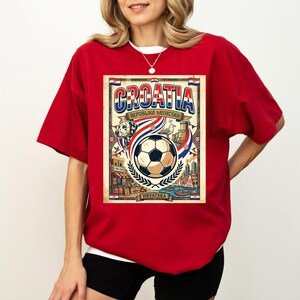 A red t-shirt with a graphic design depicting a soccer ball and various elements associated with the country of Croatia.
