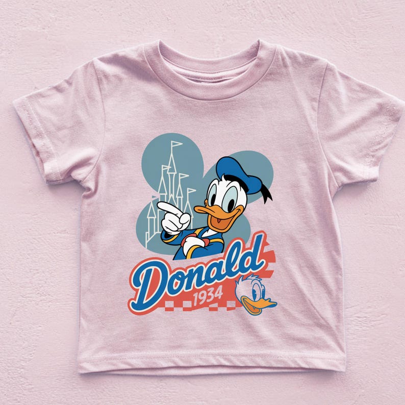 A pink t-shirt with a cartoon image of Donald Duck and the text "Donald 1934" printed on it.