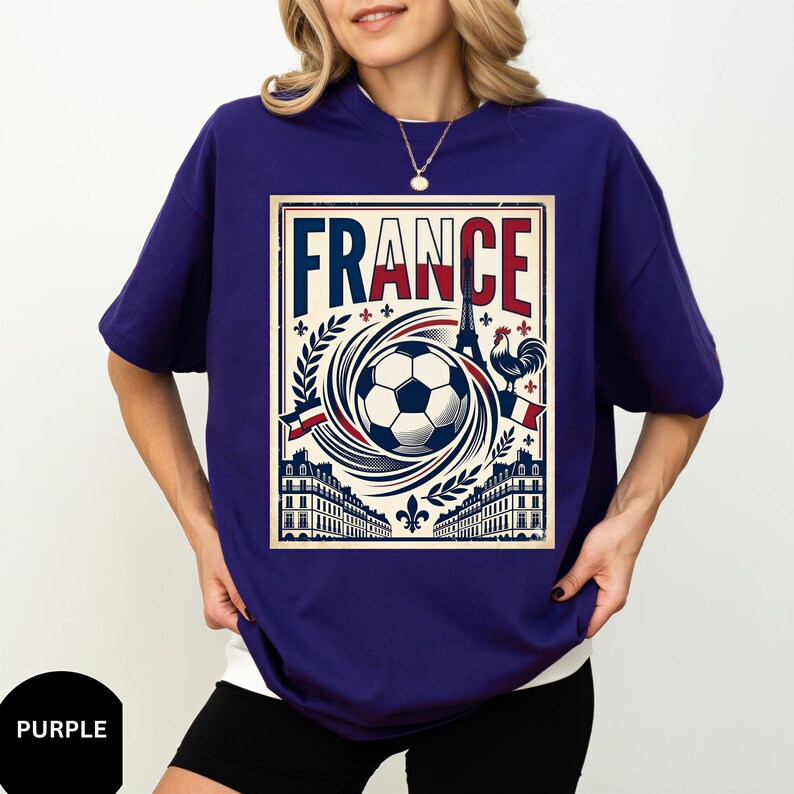 A woman wearing a purple t-shirt with a graphic design featuring a soccer ball, a rooster, and buildings, along with the word "FRANCE" prominently displayed.
