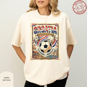 A woman wearing a white t-shirt with a graphic design featuring a soccer ball, a flag, and various elements related to the country of Croatia.