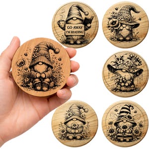 May include: A collection of six wooden coasters, each with a unique gnome design. The coasters are round and made of light-coloured wood, featuring detailed black and white illustrations of gnomes. Some gnomes are reading, others are surrounded by flowers.